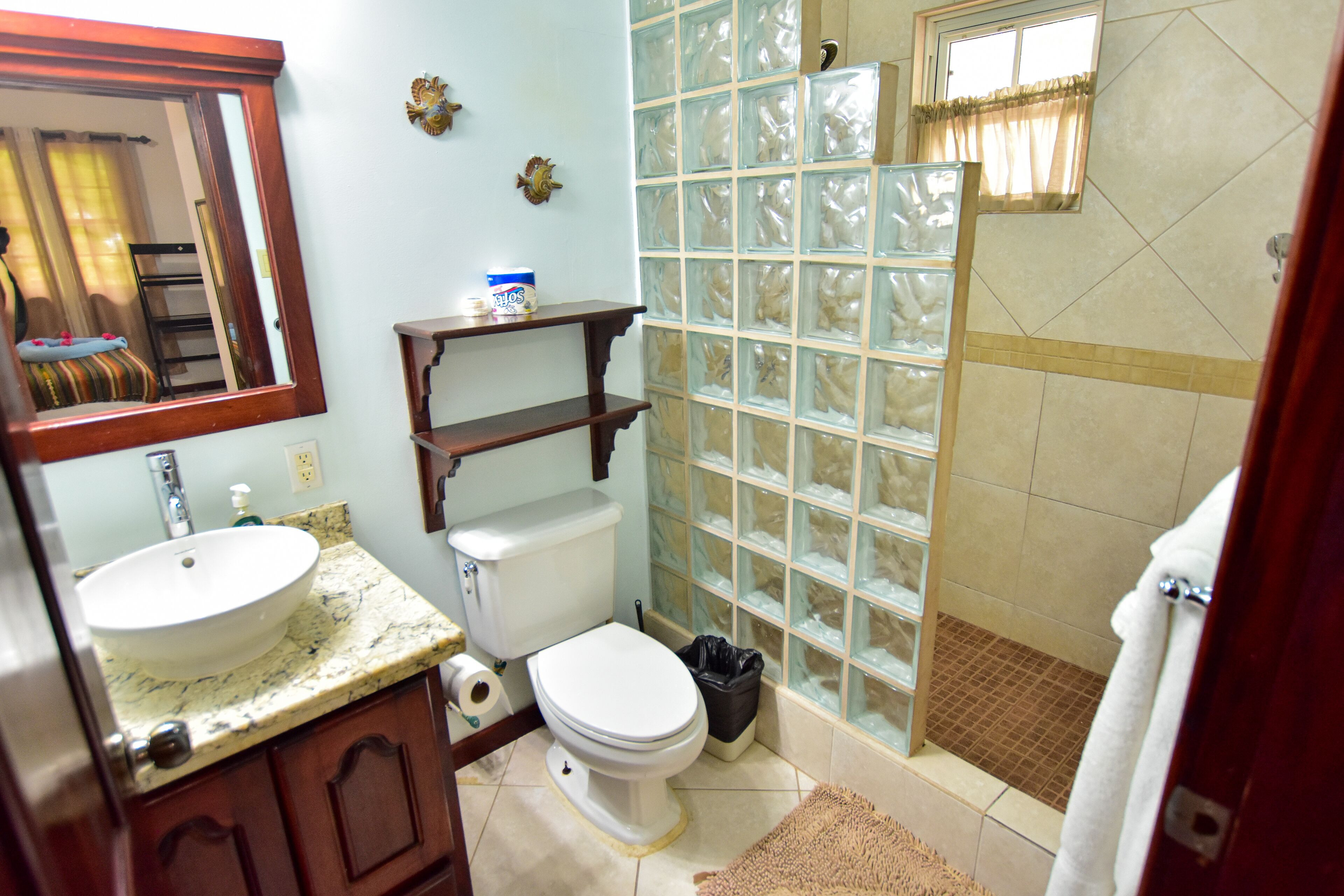 Une salle de bain avec un lavabo en marbre, des toilettes et une douche à parois de verre.