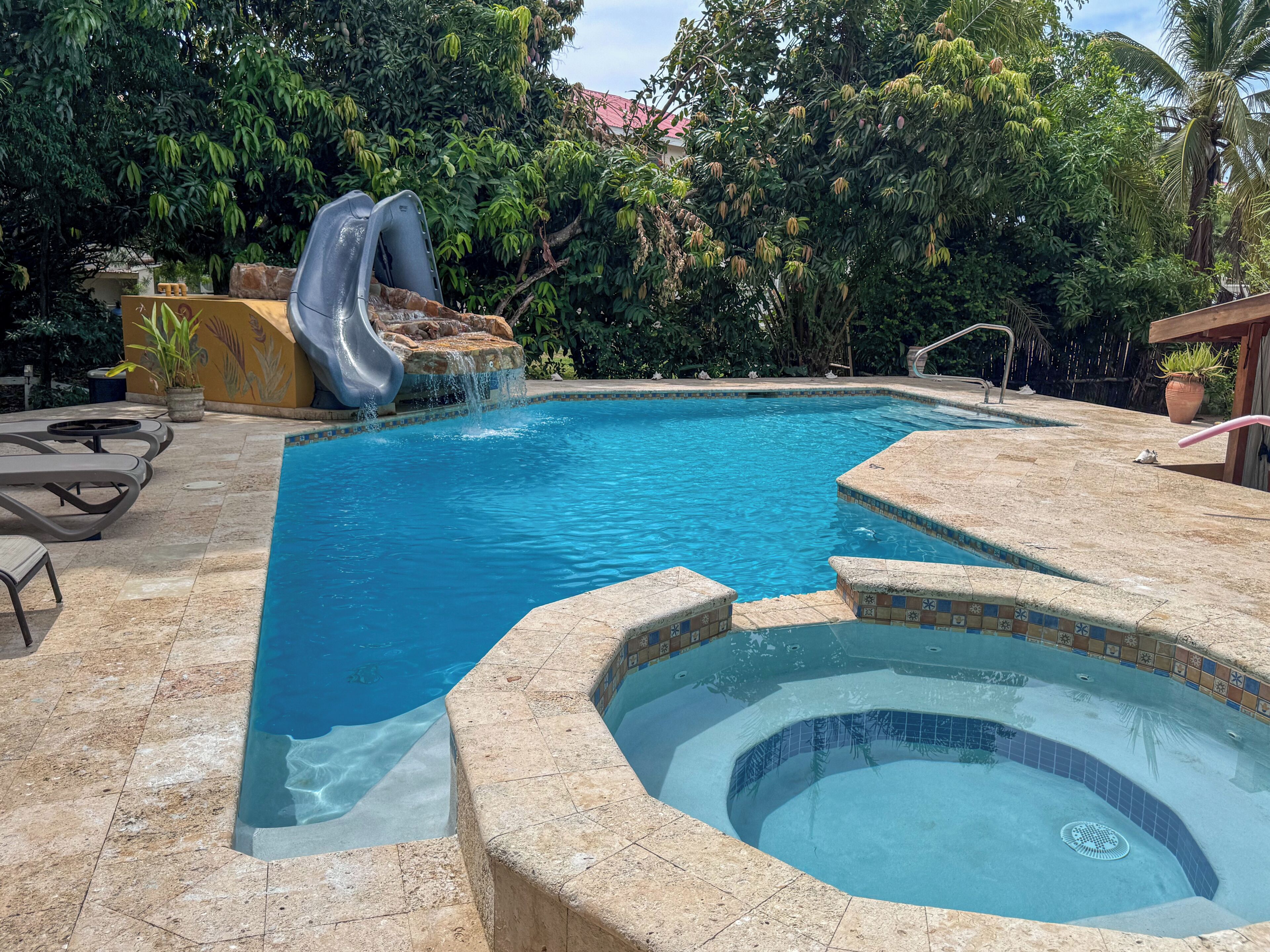 Una piscina con tobogán, jacuzzi y sillas de descanso.