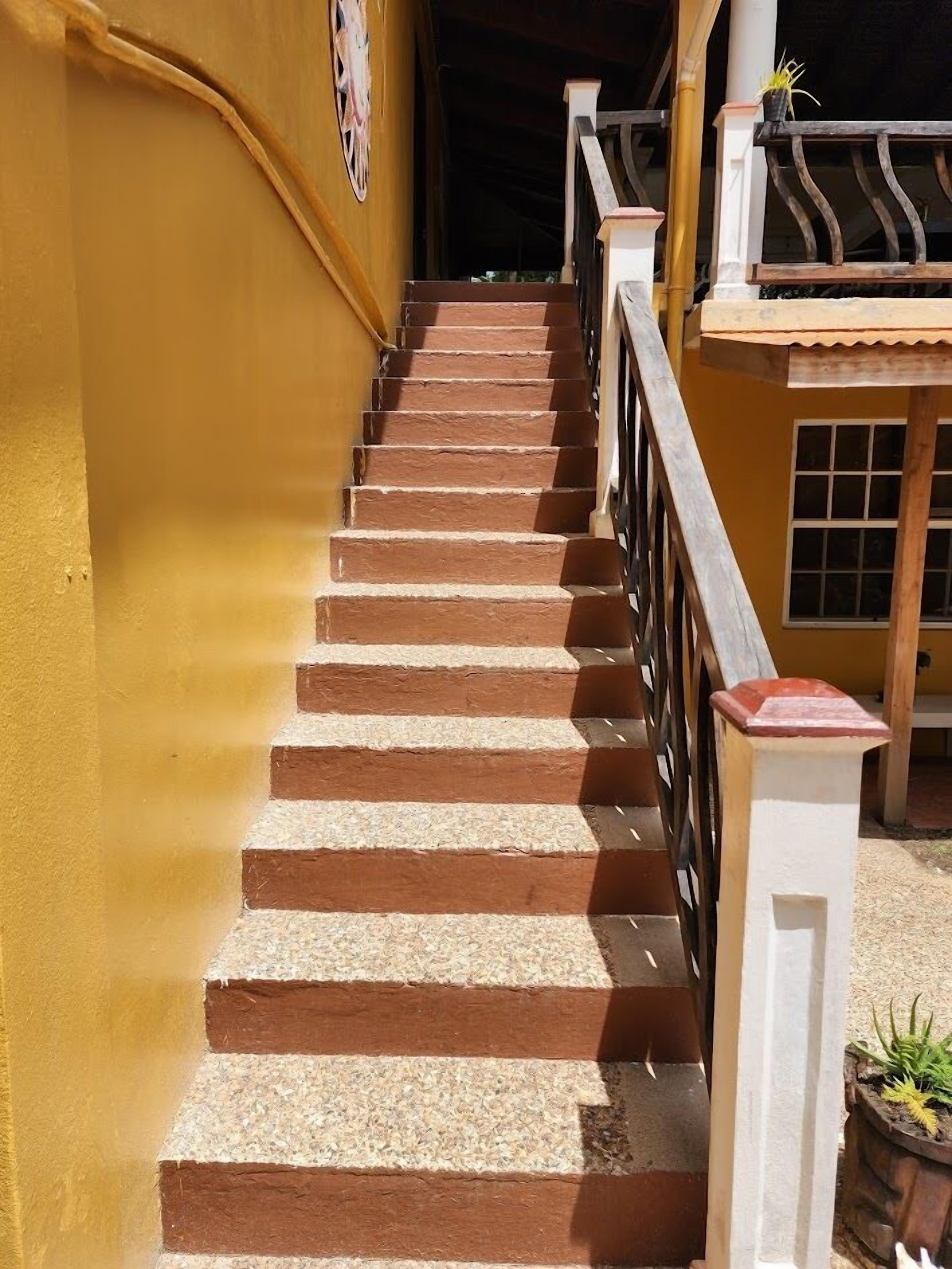 Eine Treppe mit abwechselnden braunen und beigen Stufen, weißen Spindeln und einer gelben Wand.
