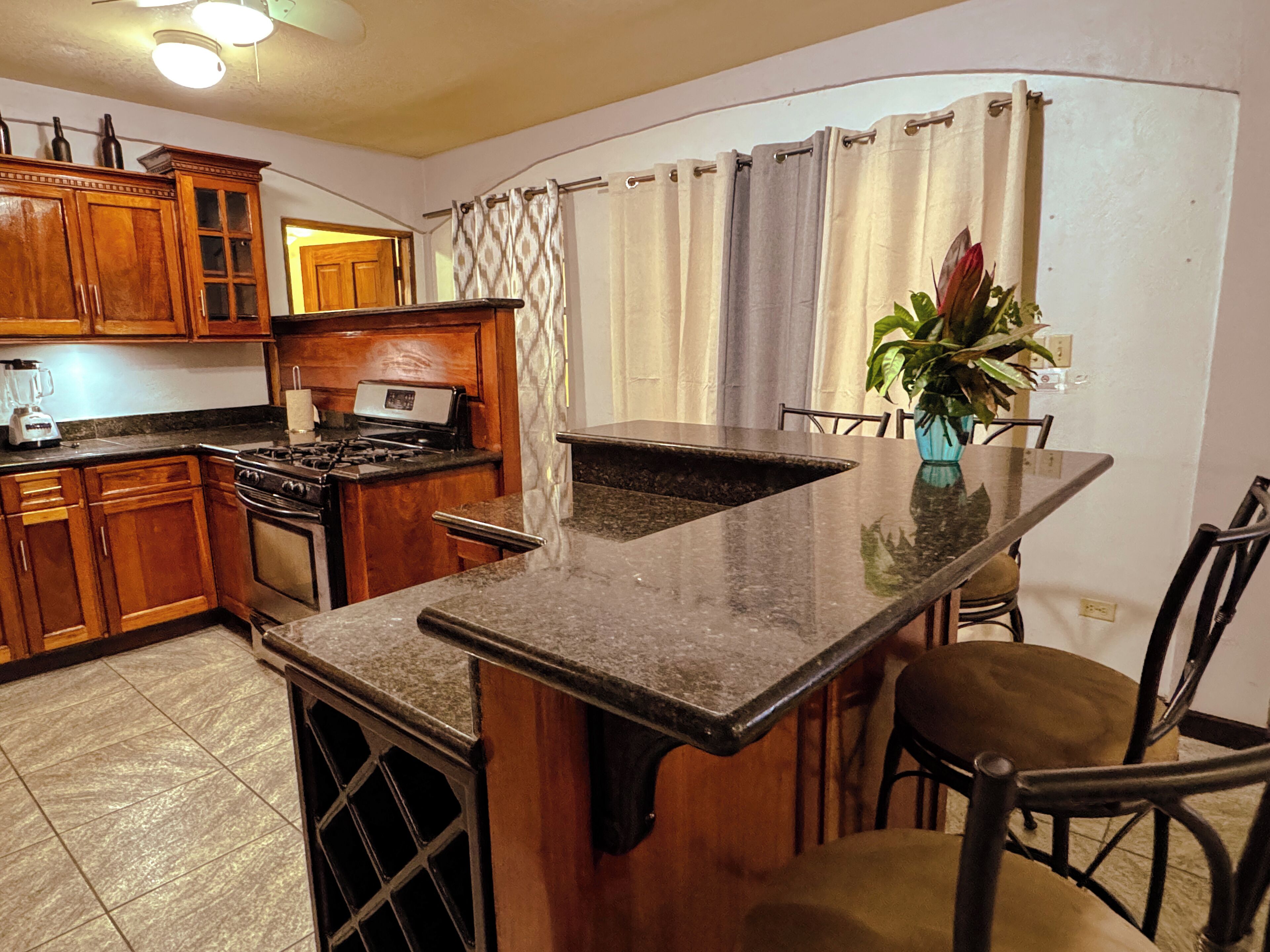 A kitchen with wooden cabinets, a stove, and a dining area with chairs and a table.