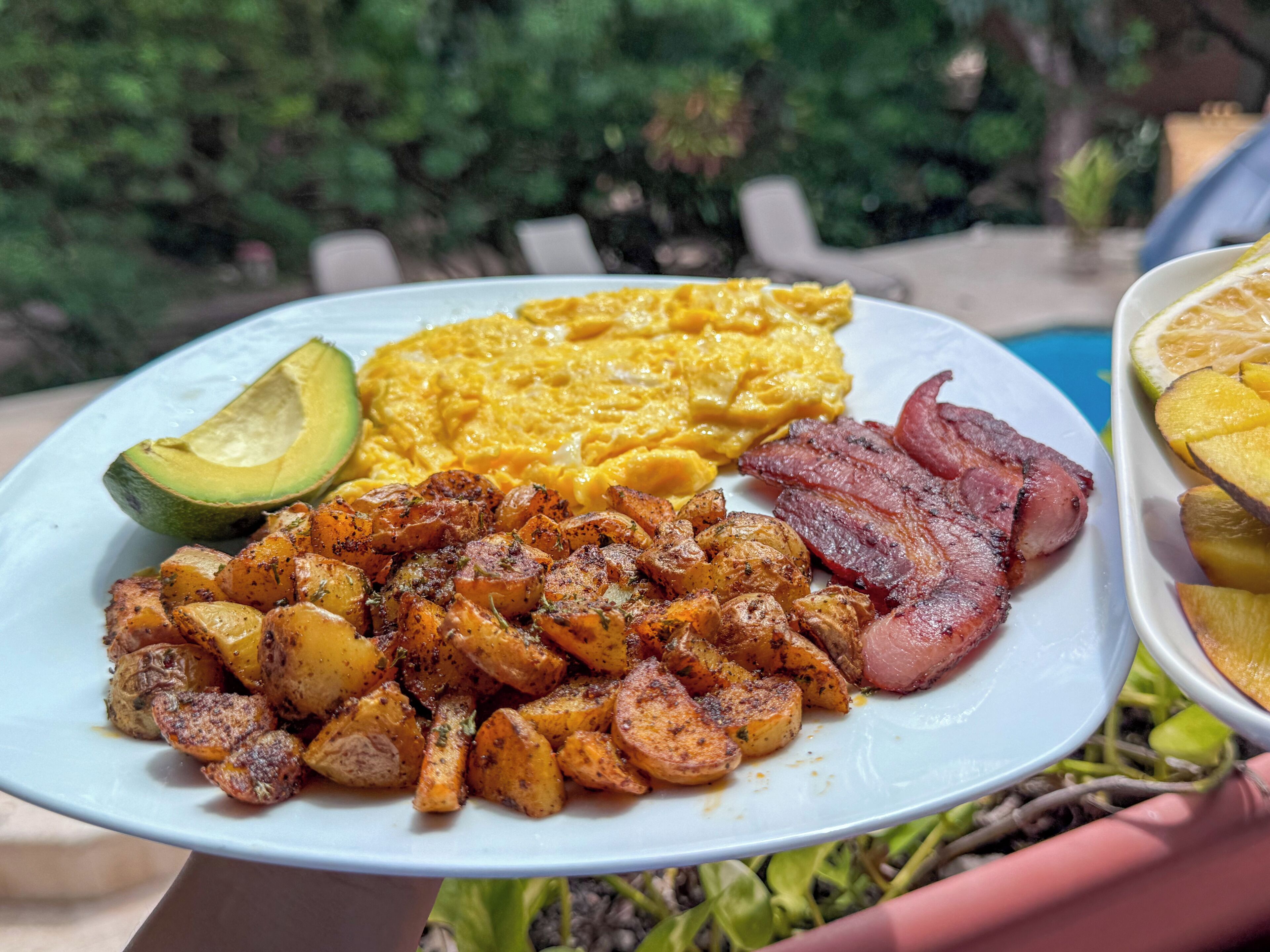 Ein Teller mit Eiern, Speck, Kartoffeln und Avocado.