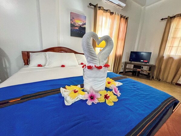A hotel room with a bed, a television, and a painting on the wall. - Caribbean Shores Bed & Breakfast (Hopkins)