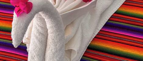 A white towel with pink flowers and green leaves, placed on a colorful striped fabric.