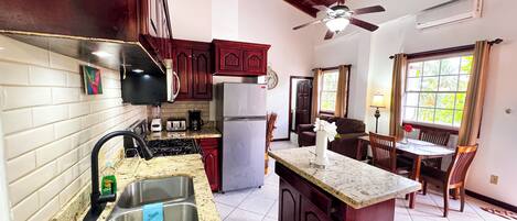 A kitchen with a sink, stove, refrigerator, and a dining area with a table and chairs.