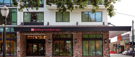 Et Hilton Garden Inn med facade i mursten, store vinduer og et skilt over indgangen.