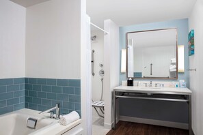 A modern bathroom with a bathtub, a shower with a glass door, a vanity with a mirror, and a towel rack. - Hilton Garden Inn Mobile Downtown (Mobile)