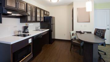 A modern kitchen with dark cabinetry, a built-in oven, and a coffee maker.