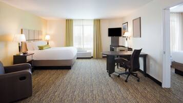 A hotel room with a bed, desk, chair, and a television.