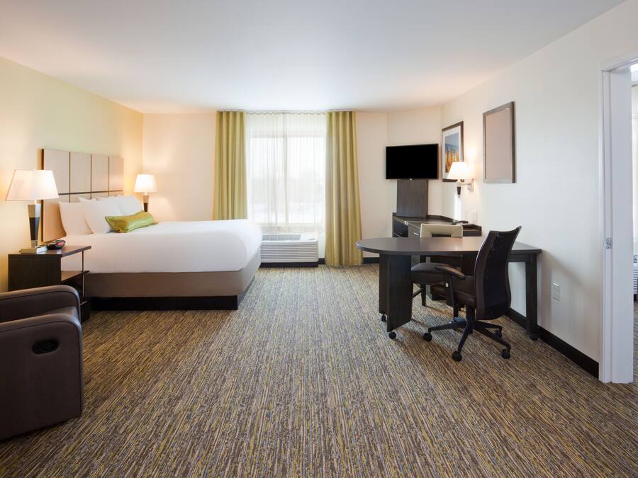A hotel room with a bed, desk, chair, and television.
