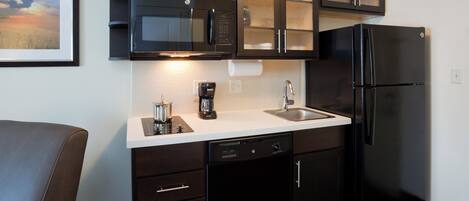 Cocina compacta con refrigerador, microondas y cafetera.