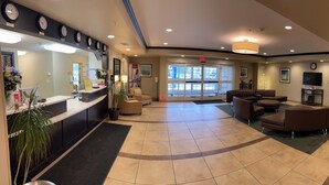 A hotel lobby with a reception desk, seating area, and a large window.