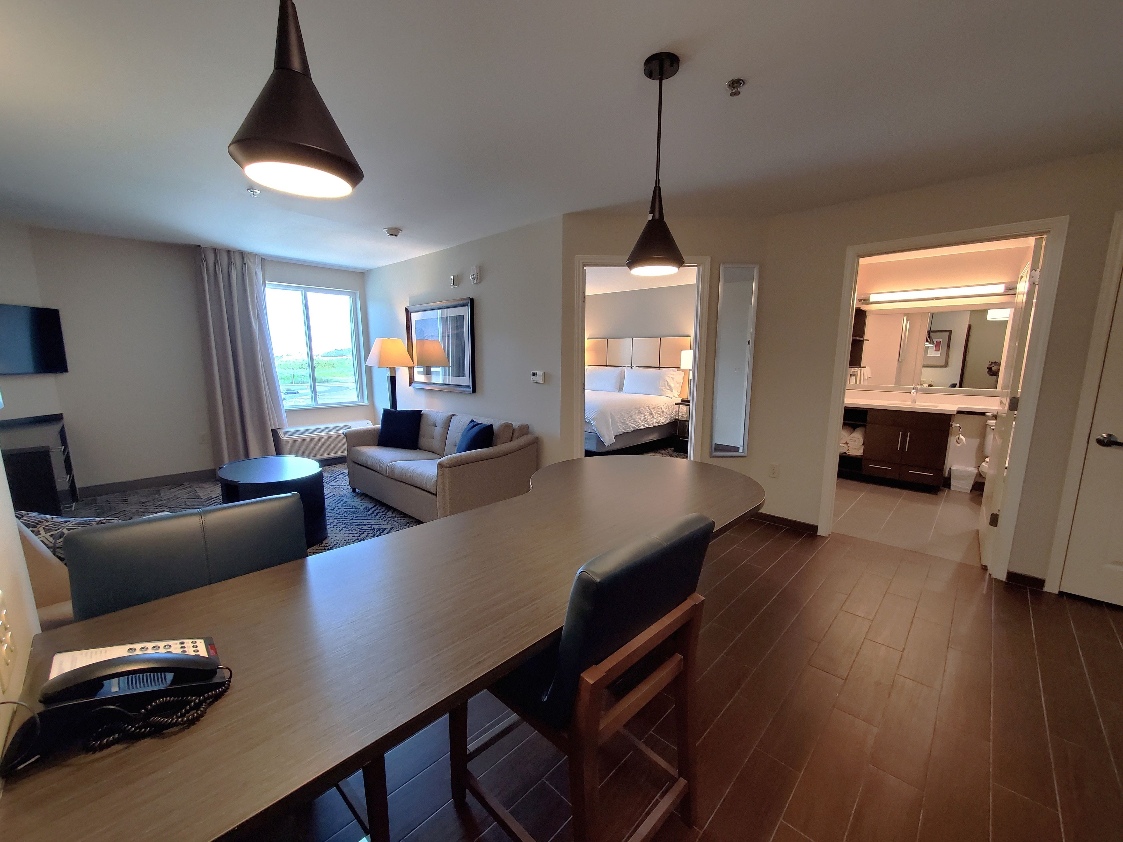 Habitación de hotel con comedor, sofá, televisor, lámpara y cama.