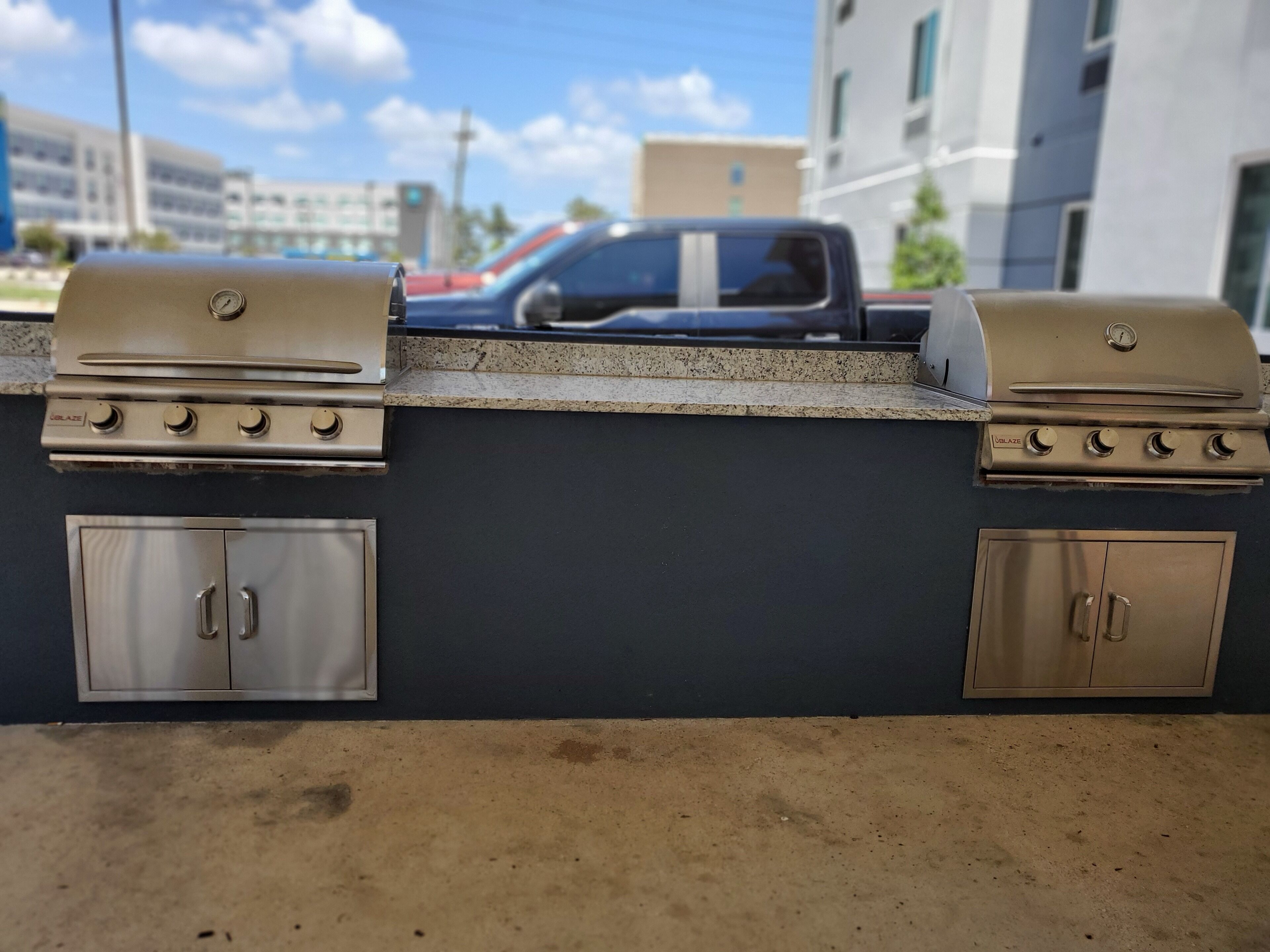 A barbecue grill with four burners and a side cabinet.