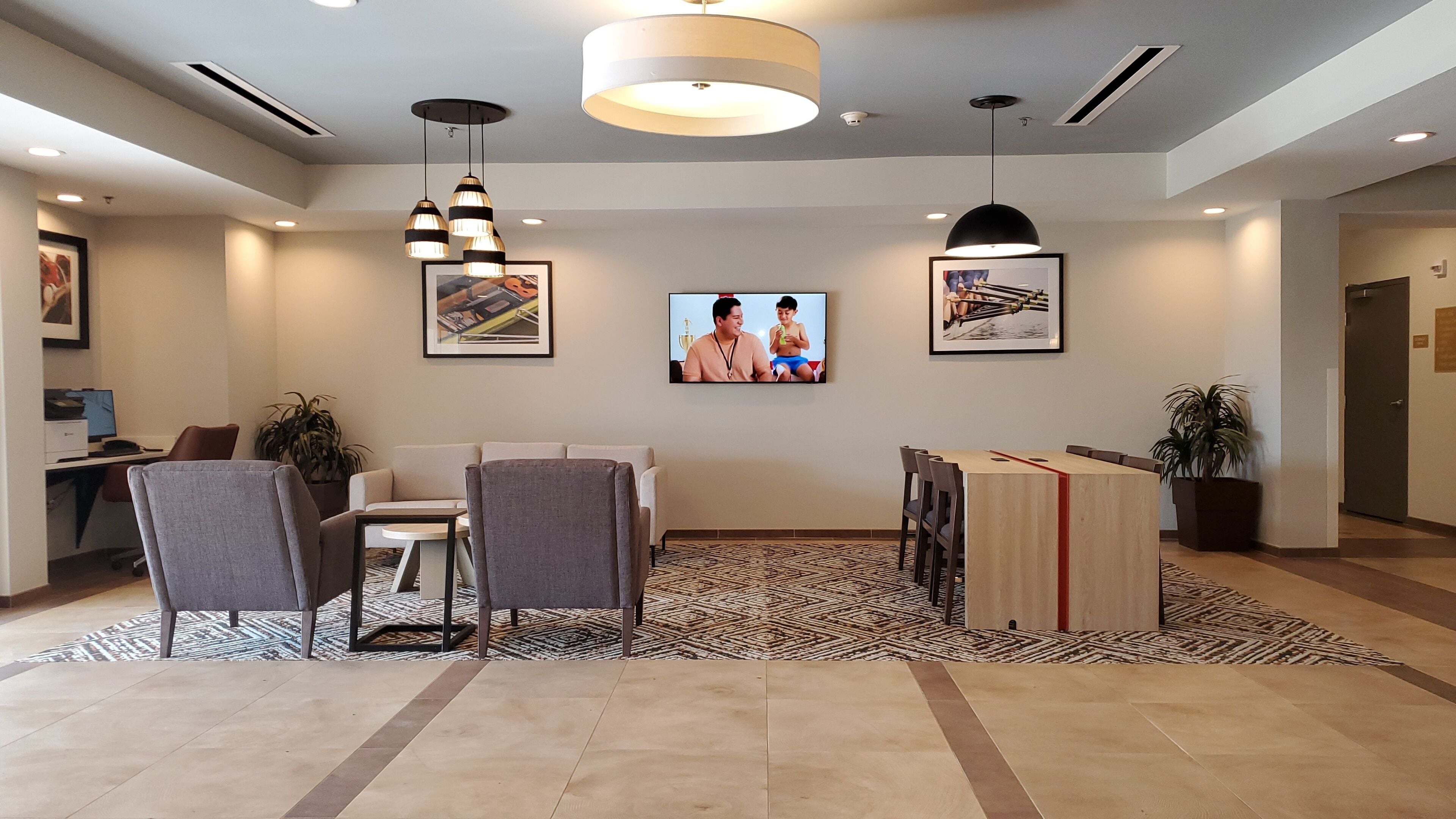 Un área de recepción moderna con un mostrador, asientos y una pantalla de televisión mostrando un programa.