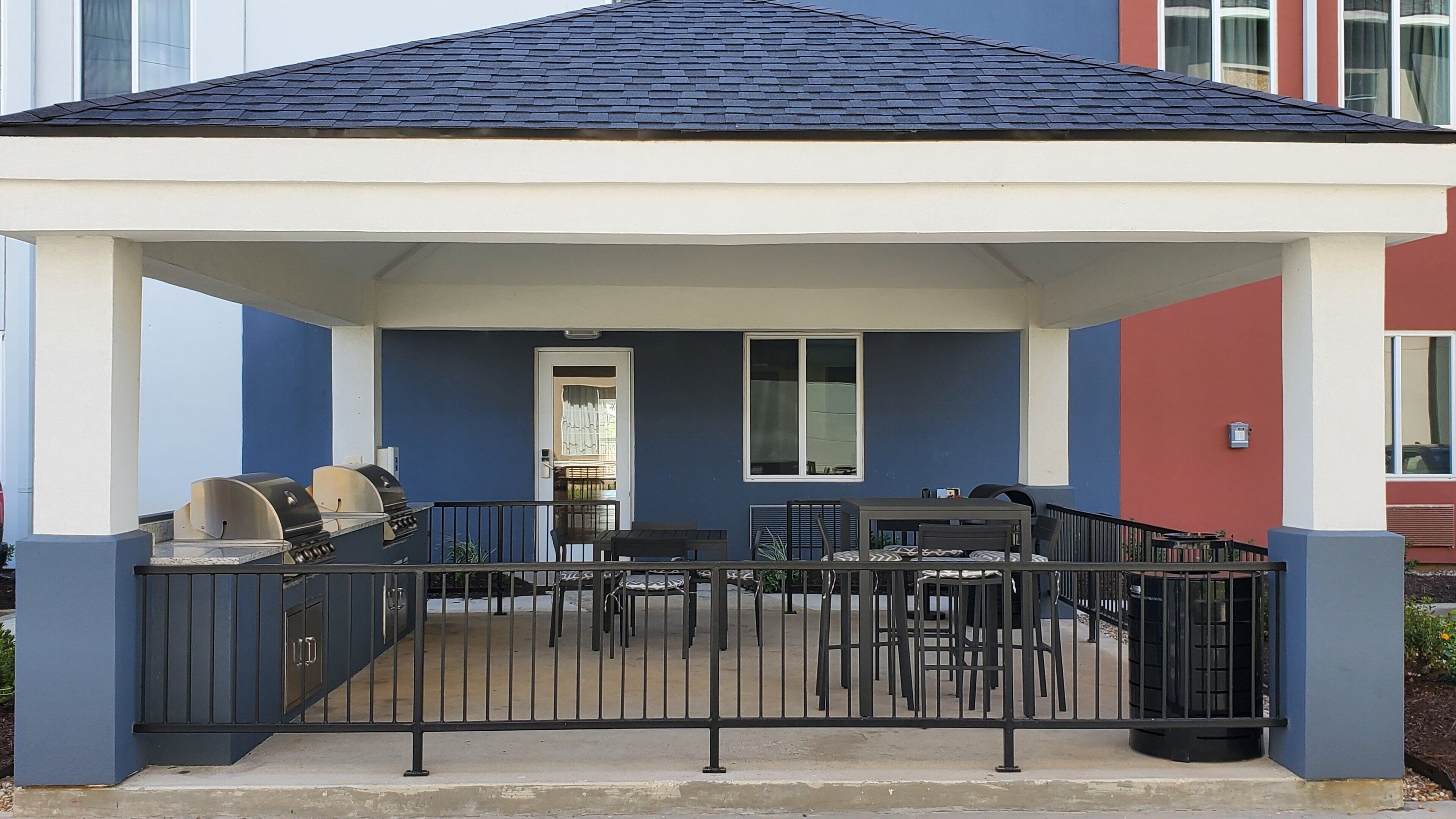 A covered outdoor patio with a grill and seating area.