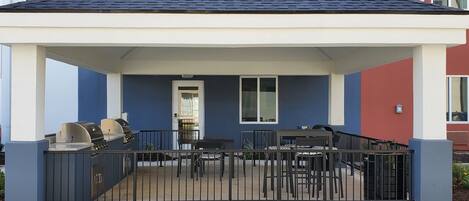 A covered outdoor patio with a grill and seating area.