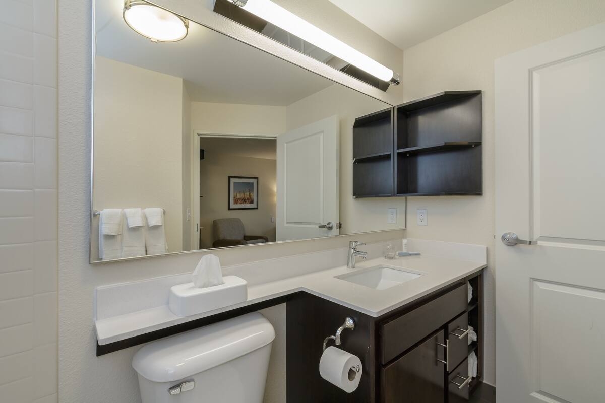 A modern bathroom with a white sink, a mirror, and a toilet.