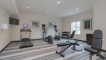 Ein Fitnessraum mit Laufband, Crosstrainer, Ergometer und einer Gewichtbank.
