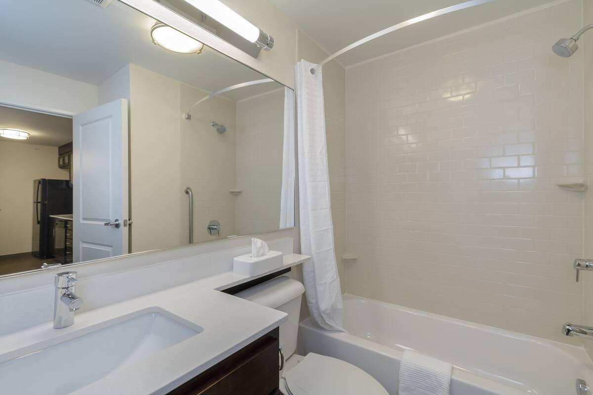 A modern bathroom with a white sink, mirror, and bathtub.