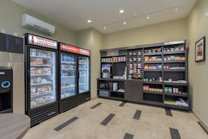 Una estación de bebidas de autoservicio con dispensadores refrigerados y un microondas.