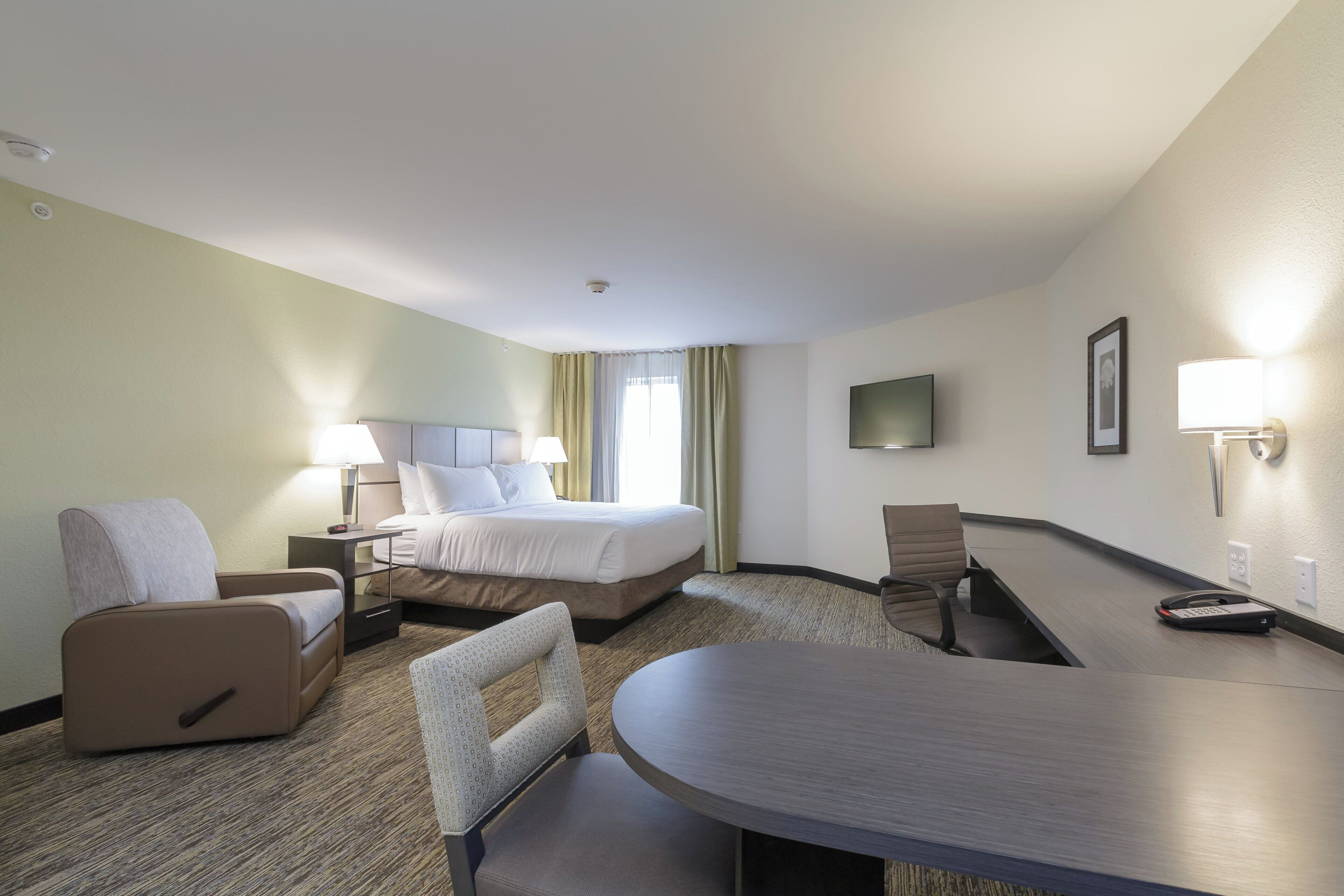 Ein Hotelzimmer mit Bett, Schreibtisch, Stuhl, Fernseher und Lampe.
