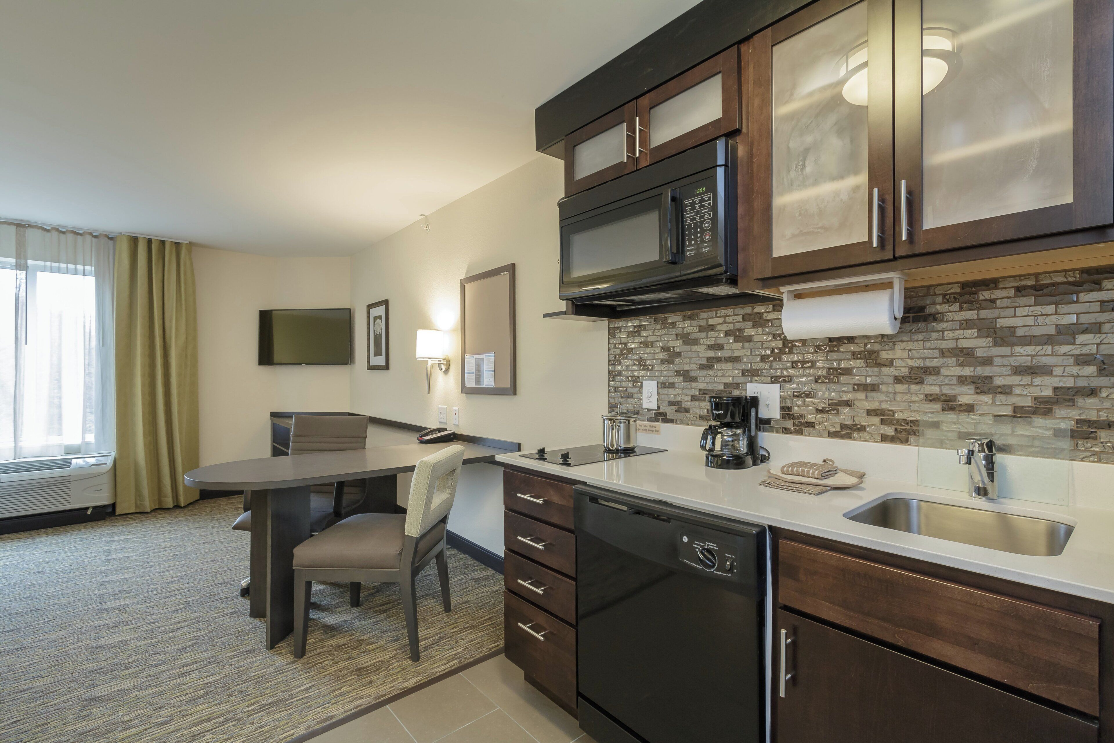 A modern kitchen with a microwave, stove, and sink. There is a dining area with a table and chairs.