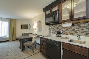 Una cocina moderna con microondas, estufa y lavamanos. Hay una zona de comedor con mesa y sillas.