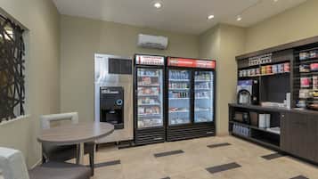 Una zona de kitchenette con refrigerador, microondas, cafetera y dispensador de bebidas.
