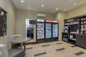 Una zona de kitchenette con refrigerador, microondas, cafetera y dispensador de bebidas.