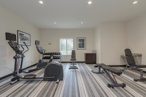 Une salle de remise en forme équipée de tapis de course, d’haltères et d’appareils d’exercice.