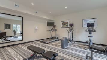 Gimnasio con caminadora, elíptica, bicicleta estática y banco de pesas.