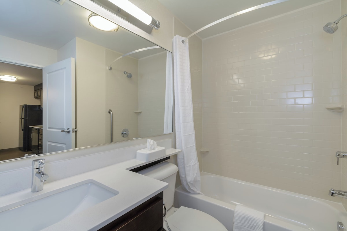 Un baño con lavamanos blanco, espejo y bañera.