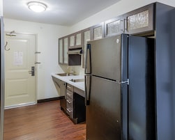 A compact kitchen with a refrigerator, sink, and cabinets.