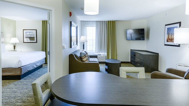 A hotel room with a bed, a sofa, a dining table, a TV, and a desk. - Candlewood Suites Lakeville I-35 by IHG (Lakeville)