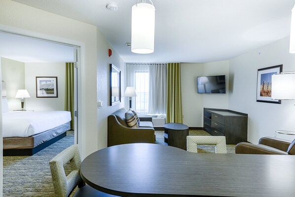 A hotel room with a bed, a sofa, a dining table, a TV, and a desk. - Candlewood Suites Lakeville I-35 by IHG (Lakeville)