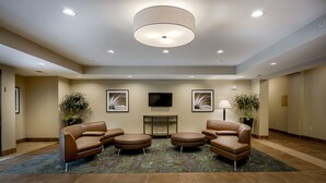 A lobby with a fireplace, seating area, and ceiling lights. - Candlewood Suites Lakeville I-35 by IHG (Lakeville)