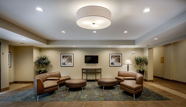 A lobby with a fireplace, seating area, and ceiling lights. - Candlewood Suites Lakeville I-35 by IHG (Lakeville)