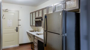 A kitchen with a black refrigerator, a sink, and wooden cabinets. - Candlewood Suites Lakeville I-35 by IHG (Lakeville)