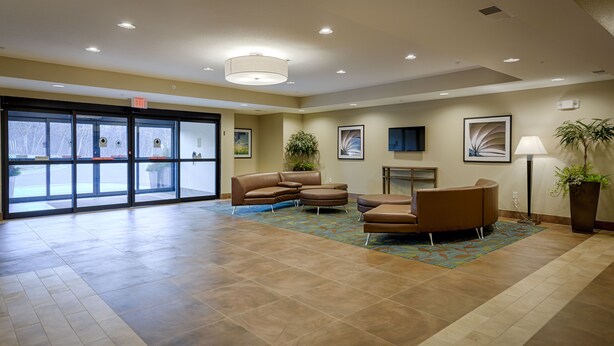 A spacious lobby with a large entrance, a sofa, a chair, and a potted plant. - Candlewood Suites Lakeville I-35 by IHG (Lakeville)