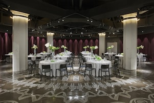 Un salón de banquetes con mesas redondas, sillas y centros de mesa florales.