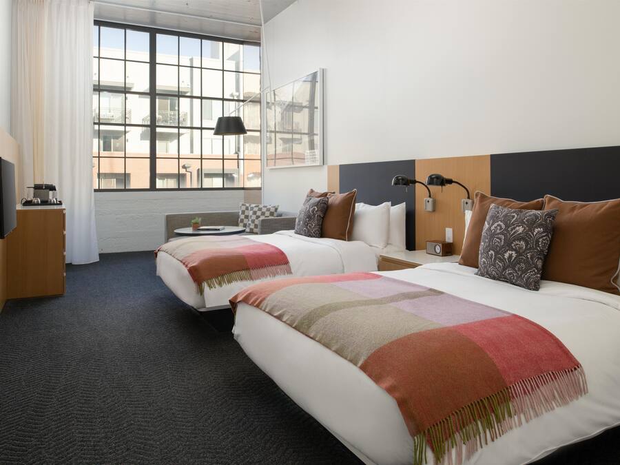 Een hotelkamer met twee bedden, een groot raam, een flatscreen televisie en een bureau met een lamp.