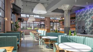 Um café moderno com diferentes opções de assentos, incluindo cabines e mesas, e uma área de bar com balcão.
