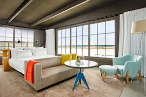 A modern hotel room with a large bed, a sofa, a round table, and a view of the countryside. - Fordson Hotel, in the Unbound Collection by Hyatt (Oklahoma City)
