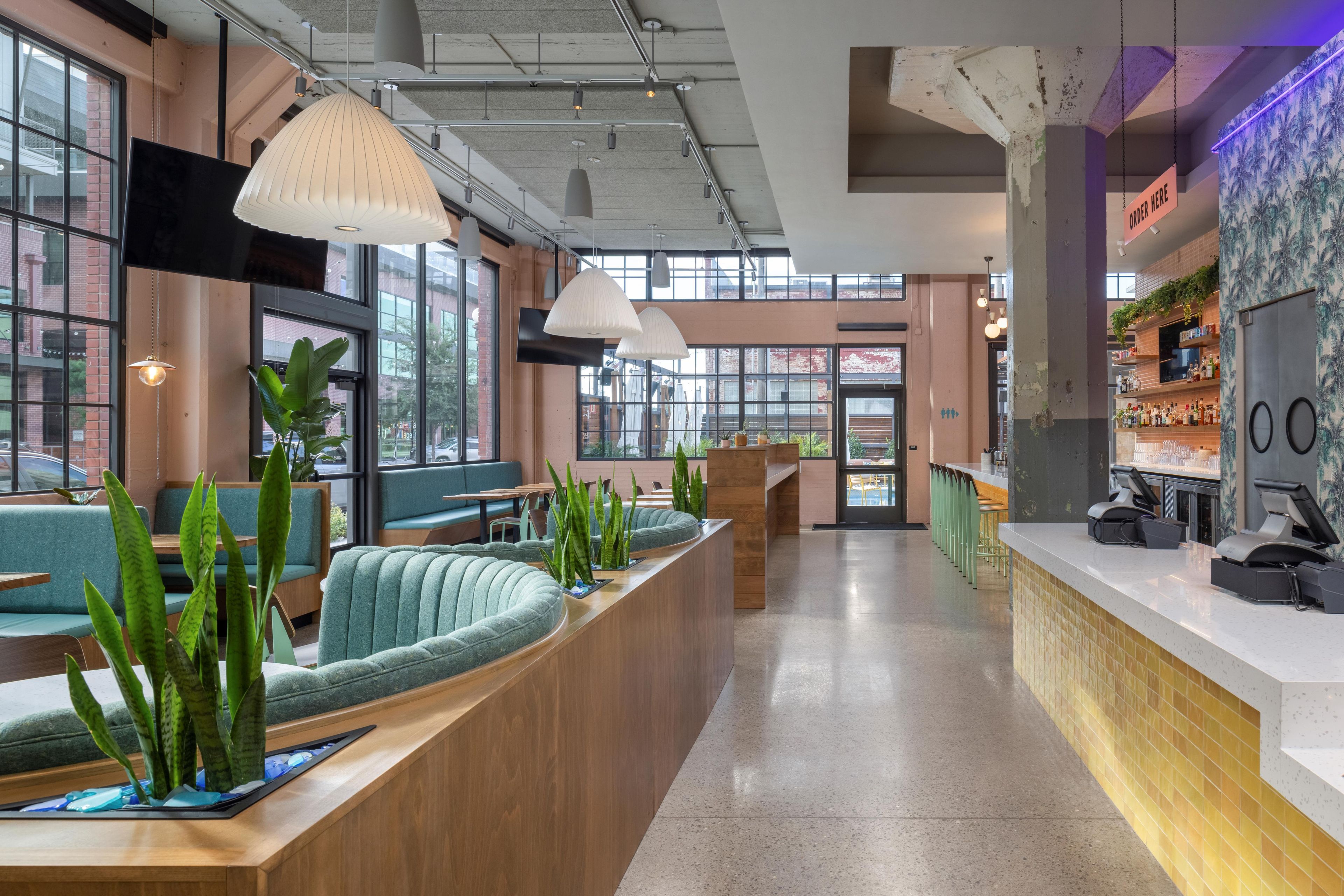 A modern bar area with seating, bar counter, and a view of the street.