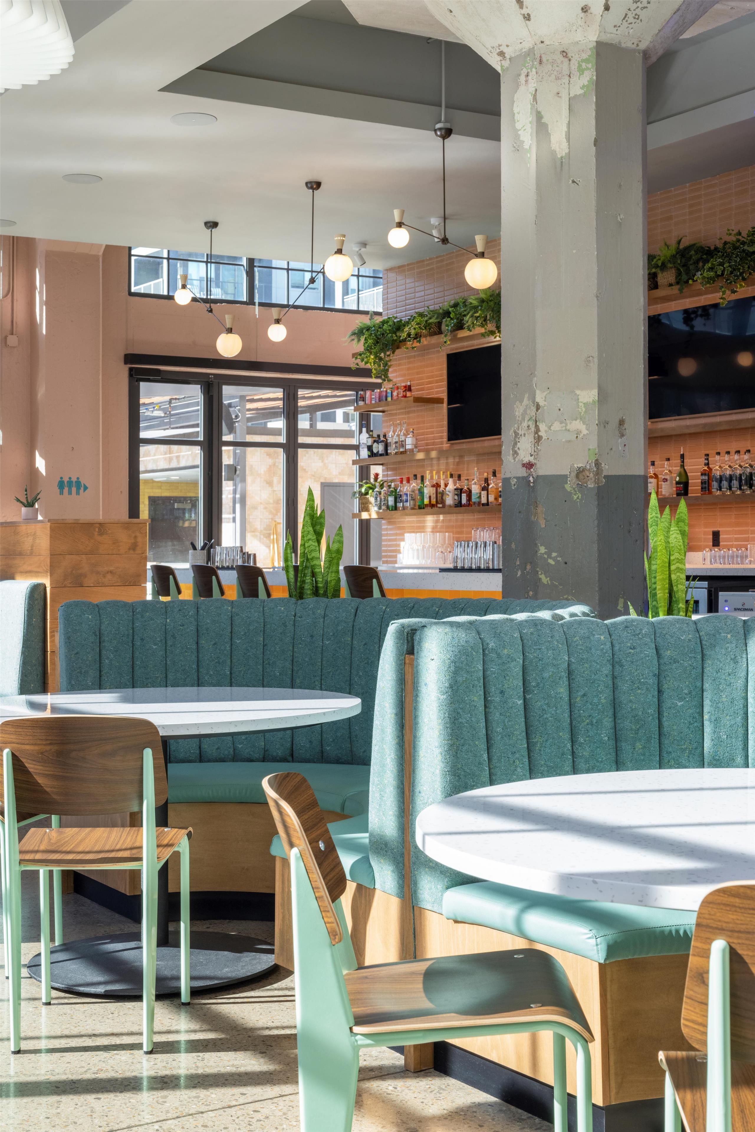 A modern bar area with seating, pendant lighting, and a bar stocked with bottles.