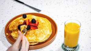 Ein Teller Pfannkuchen mit Beeren und ein Glas Orangensaft.