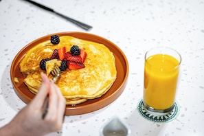 A plate of pancakes with berries and a glass of orange juice.