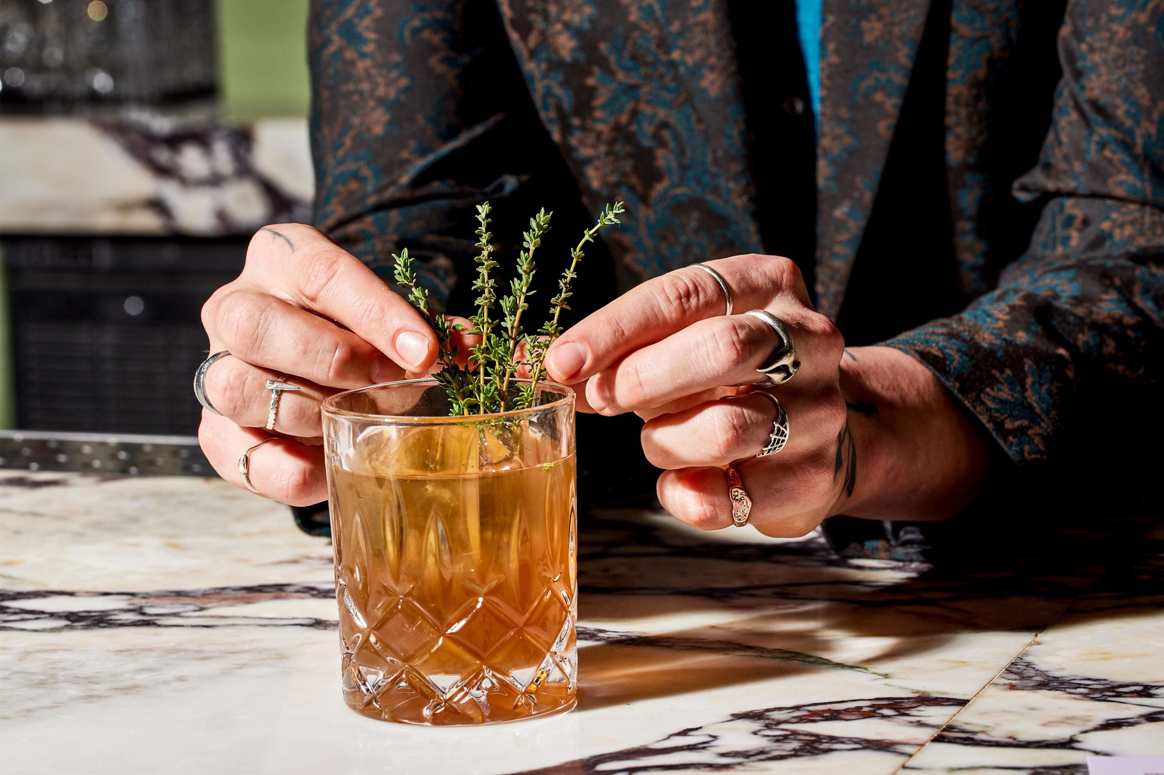 A person holding a glass mug with a plant inside, wearing a patterned sleeve.