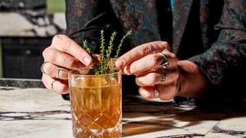 A person holding a glass mug with a plant inside, wearing a patterned sleeve.