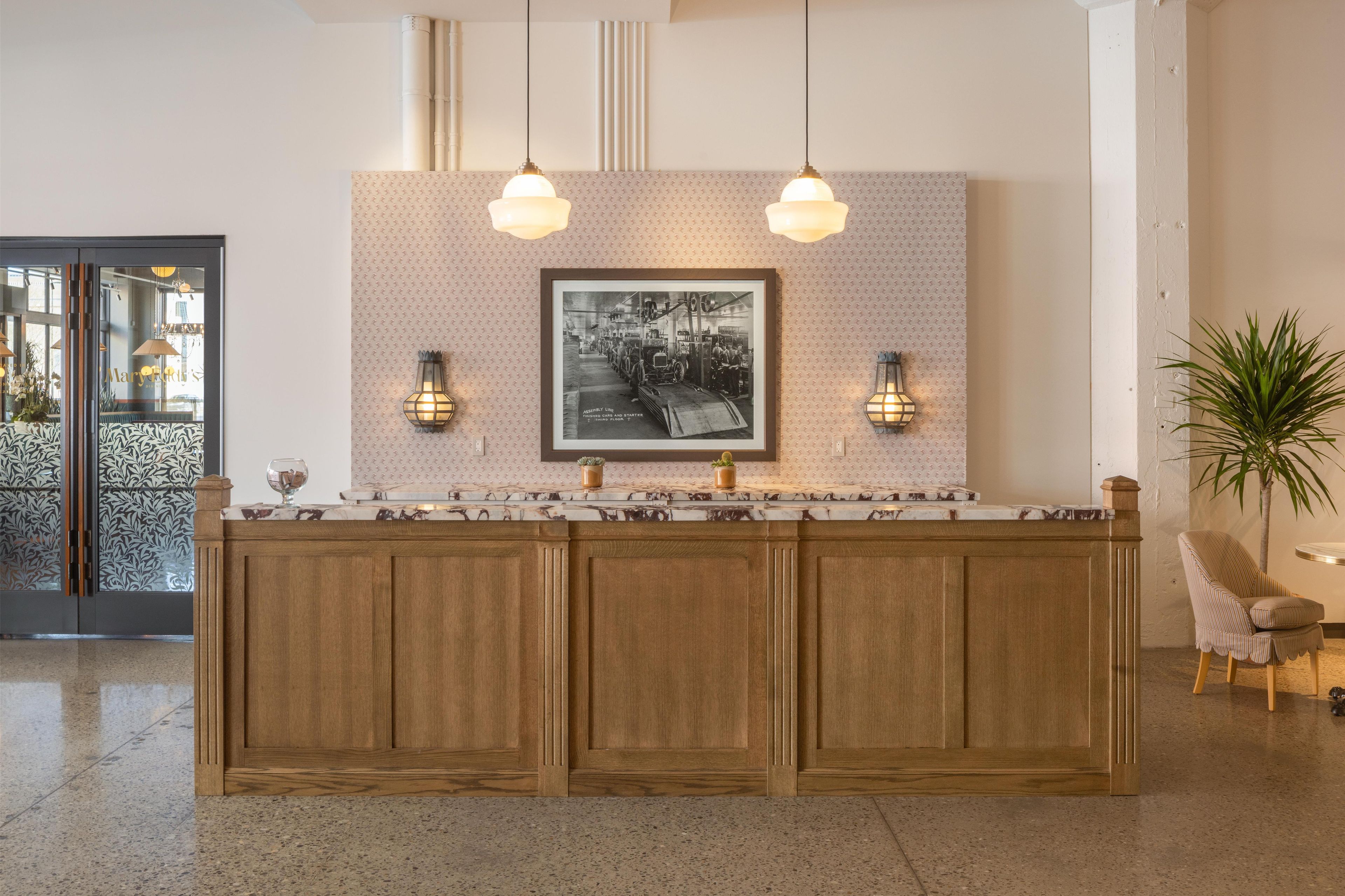 A reception area with a marble counter, wooden paneling, two pendant lights, and a framed black and white photo on the wall.